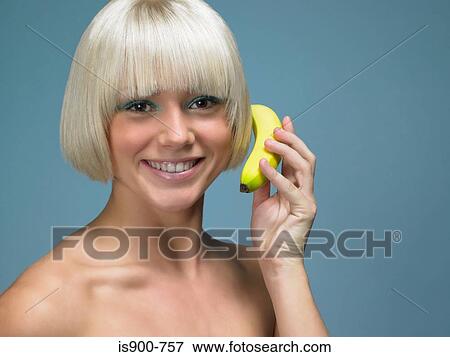 Stock Photo - Blond woman using banana as telephone. Fotosearch