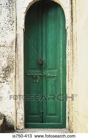 Stock Image - Green door in arch. Fotosearch