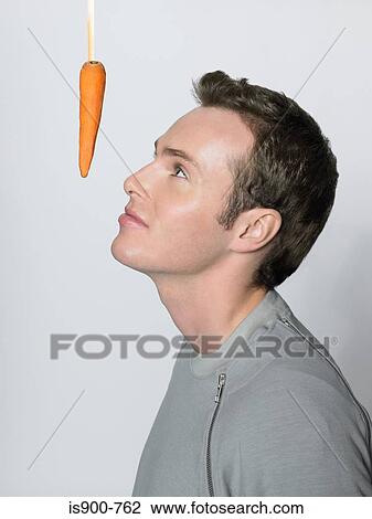 Stock Image - Man looking at dangling carrot. Fotosearch