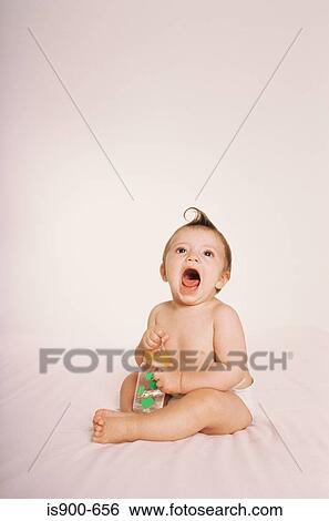 Stock Photograph - Baby holding baby bottle. Fotosearch