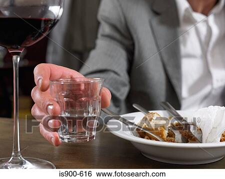 Man sitting with glass of water and finished meal View Large Photo Image Stock Photograph - Man sitting with glass of water and finished meal. Fotosearch
