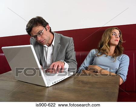 Stock Image - Woman bored as man works on computer. Fotosearch