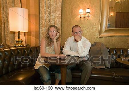 Stock Image - Couple in a bar ignoring each other. Fotosearch