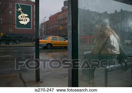 Stock Photo - Man looking at billboard from bus shelter. Fotosearch