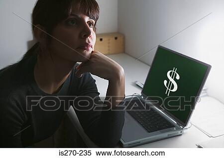 Stock Photography - Woman daydreaming with dollar sign on her laptop. Fotosearch