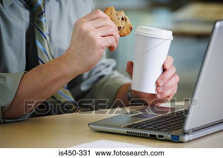 Man at desk with coffee and a cookie View Large Photo Image Stock Image - Man at desk with coffee and a cookie. Fotosearch