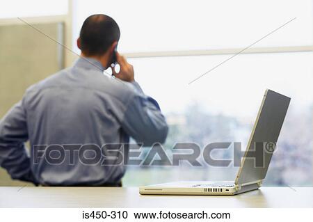 Man on cellphone and laptop View Large Photo Image Stock Image - Man on cellphone and laptop. Fotosearch