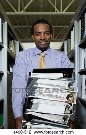 Stock Image - Man with pile of ring binders. Fotosearch