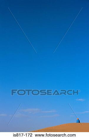 Stock Image - Person on a sand dune in the sahara. Fotosearch