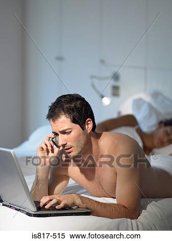 Stock Photography - Man working as wife sleeps. Fotosearch