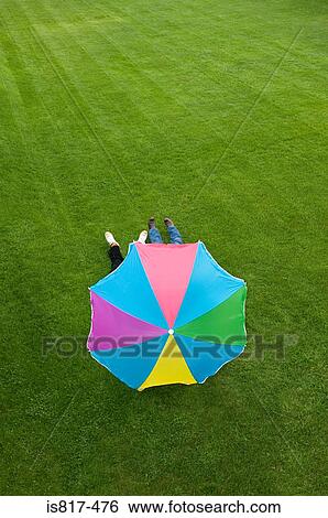 People lying under a parasol View Large Photo Image Stock Photograph - People lying under a parasol. Fotosearch