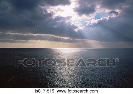 Stock Photo - Sunlight through clouds over the sea. Fotosearch