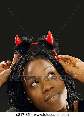 Stock Image - Woman wearing devil horns. Fotosearch