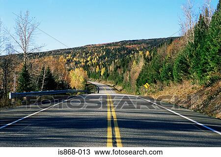 Stock Image - Deserted highway through forest. Fotosearch