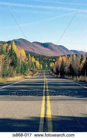Deserted highway through trees and mountains View Large Photo Image Stock Photo - Deserted highway through trees and mountains. Fotosearch