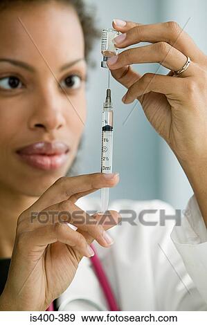 Stock Photo - Doctor preparing syringe. Fotosearch
