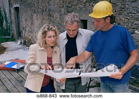 Stock Image - Couple and builder with plans. Fotosearch