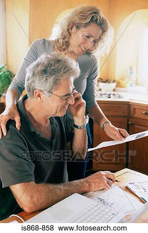 Stock Photo - Couple with laptop and paperwork. Fotosearch