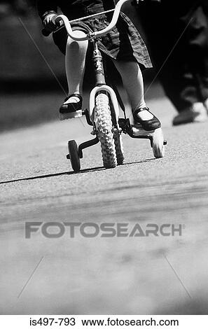 Stock Image - A girl learning to ride a bike. Fotosearch