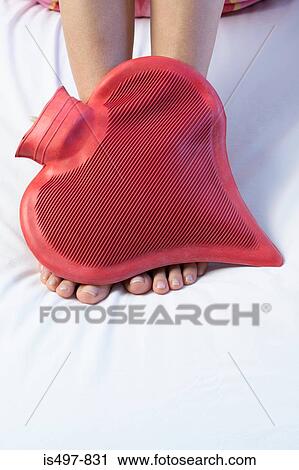 Stock Image - Feet and a heart shaped hot water bottle. Fotosearch