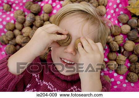 A girl covering her eyes with walnuts View Large Photo Image Stock Photo - A girl covering her eyes with walnuts. Fotosearch