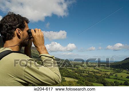 Man looking at glenariff with binoculars View Large Photo Image Stock Photo - Man looking at glenariff with binoculars. Fotosearch