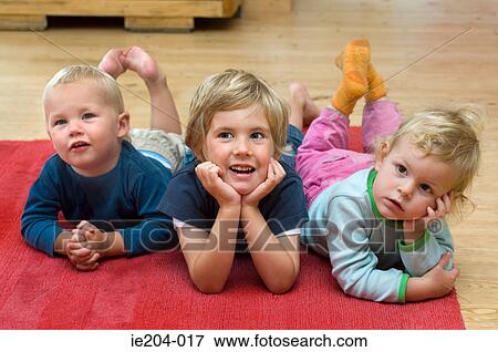 Stock Photo - Three children lying on the floor. Fotosearch