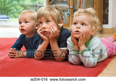 Three children lying on the floor View Large Photo Image Stock Photograph - Three children lying on the floor. Fotosearch