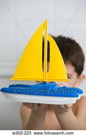 Boy holding a toy boat View Large Photo Image Stock Image - Boy holding a toy boat. Fotosearch