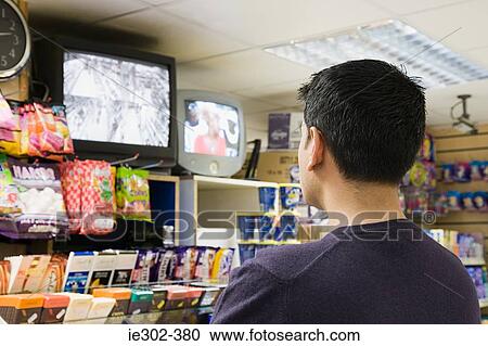 Man watching television in shop View Large Photo Image Stock Image - Man watching television in shop. Fotosearch