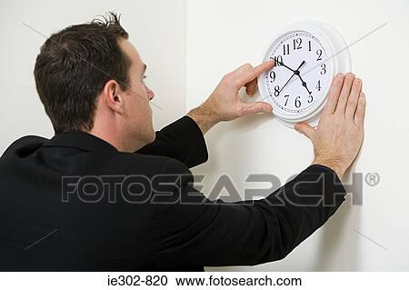 A businessman adjusting the hands on a clock View Large Photo Image Stock Image - A businessman adjusting the hands on a clock. Fotosearch