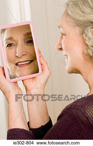 Picture - A senior woman looking in a mirror. Fotosearch