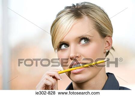 An office worker biting on a pencil View Large Photo Image Stock Photo - An office worker biting on a pencil. Fotosearch