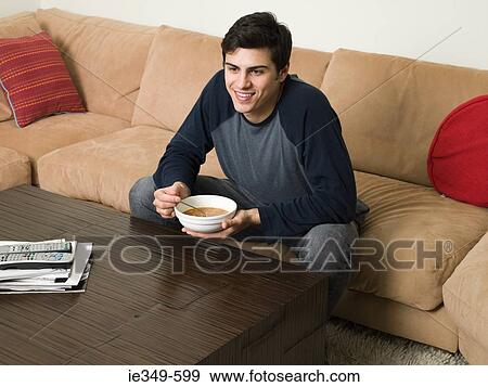 Stock Photo - Man on sofa with soup. Fotosearch