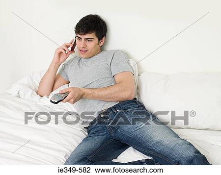 Man with cellphone and remote control View Large Photo Image Stock Image - Man with cellphone and remote control. Fotosearch