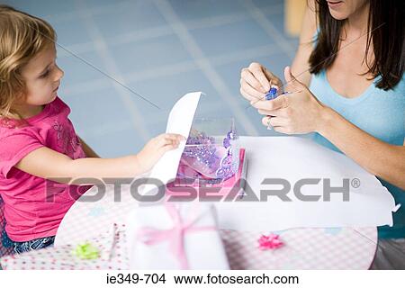Mother and daughter wrapping gift View Large Photo Image Picture - Mother and daughter wrapping gift. Fotosearch