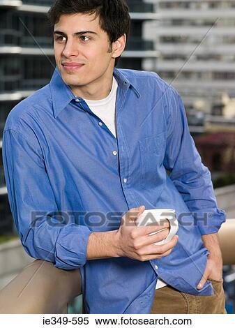 Young man with hot drink View Large Photo Image Stock Photography - Young man with hot drink. Fotosearch