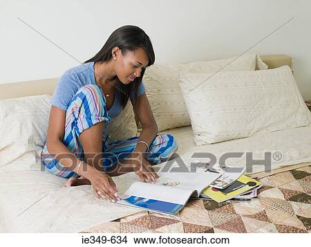 Young woman on bed with magazines View Large Photo Image Picture - Young woman on bed with magazines. Fotosearch