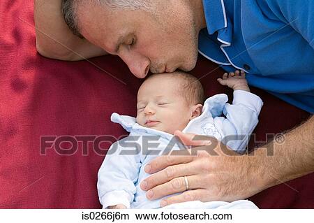 Picture - A father kissing his baby daughter on the head. Fotosearch