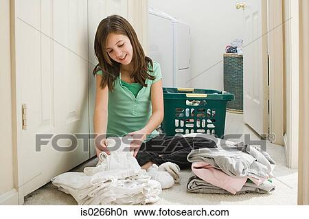 A girl arranging piles of laundry View Large Photo Image Picture - A girl arranging piles of laundry. Fotosearch