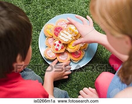 Stock Image - A boy and girl having cakes at a party. Fotosearch