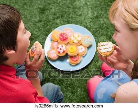 Stock Image - A boy and girl having cakes at a party. Fotosearch