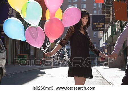 Stock Image - A couple holding hands and woman holding balloons. Fotosearch