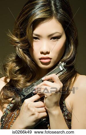 A woman holding a gun View Large Photo Image Stock Photo - A woman holding a gun. Fotosearch