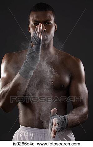 Stock Image - A young man rubbing his hands with chalk. Fotosearch