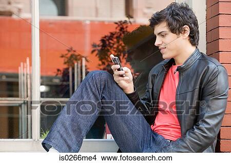 A young man texting View Large Photo Image Picture - A young man texting. Fotosearch