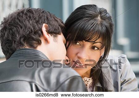 A young man whispering to a woman View Large Photo Image Stock Photo - A young man whispering to a woman. Fotosearch