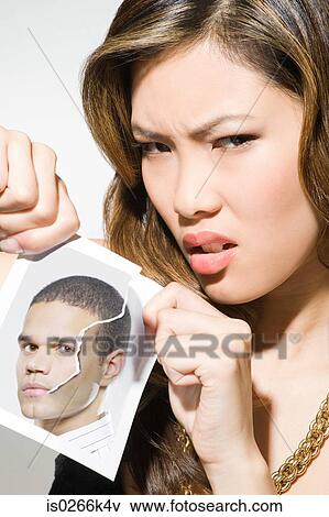 Stock Photo - A young woman ripping a photograph of a man. Fotosearch
