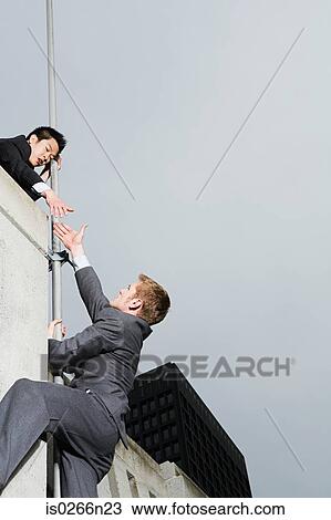 Businessman reaching colleague over wall View Large Photo Image Stock Image - Businessman reaching colleague over wall. Fotosearch