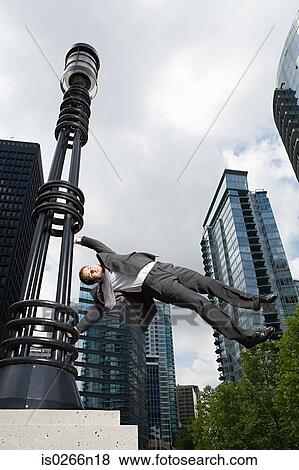 Businessman swinging on lamppost View Large Photo Image Stock Photo - Businessman swinging on lamppost. Fotosearch